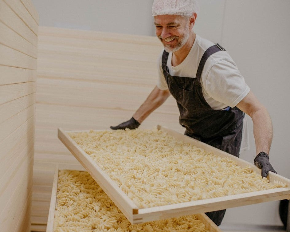 Duro Pasta founder Jesse Hegg stacking racks of dried pasta